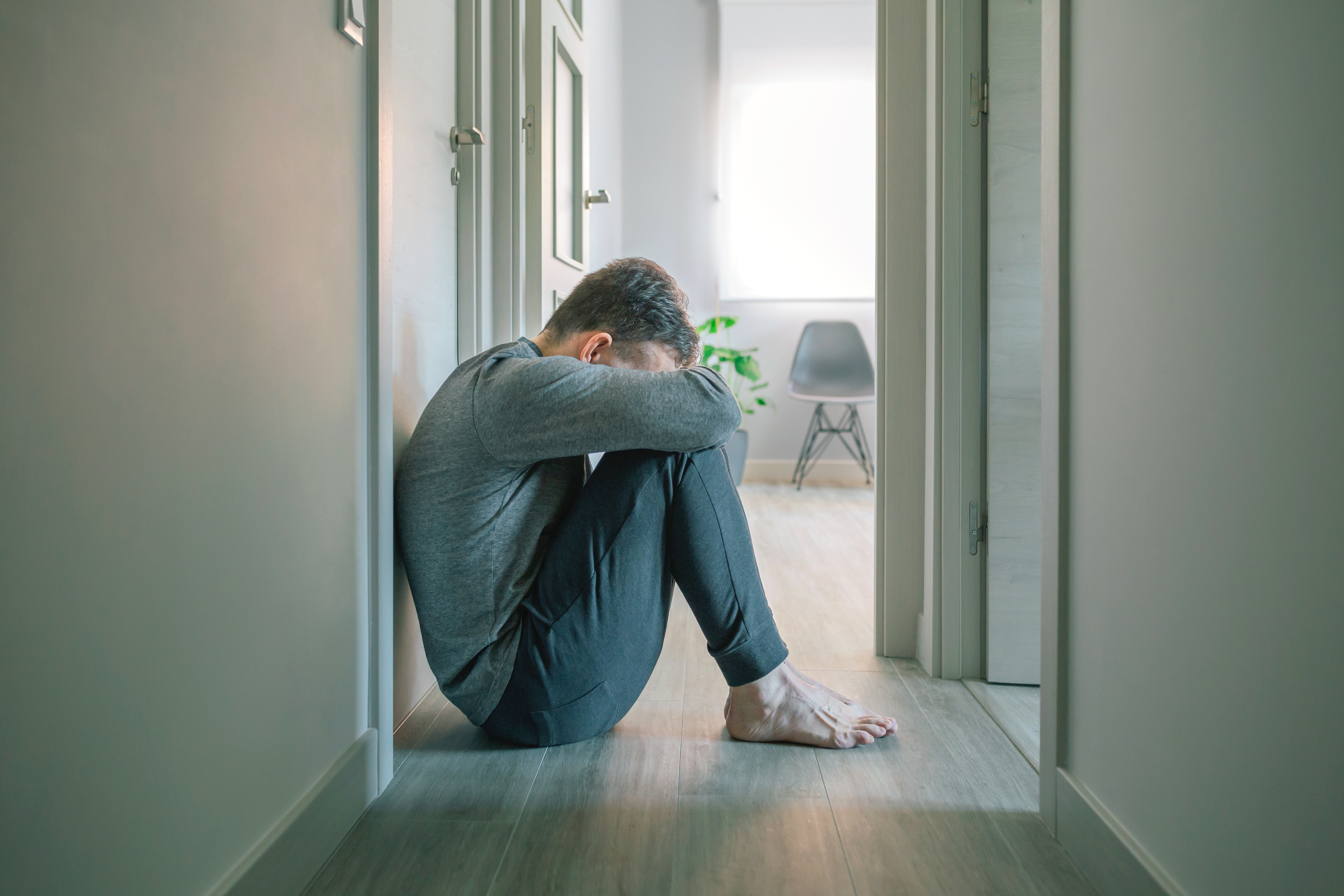 Man with mental disorder and suicidal thoughts crying sitting on the floor