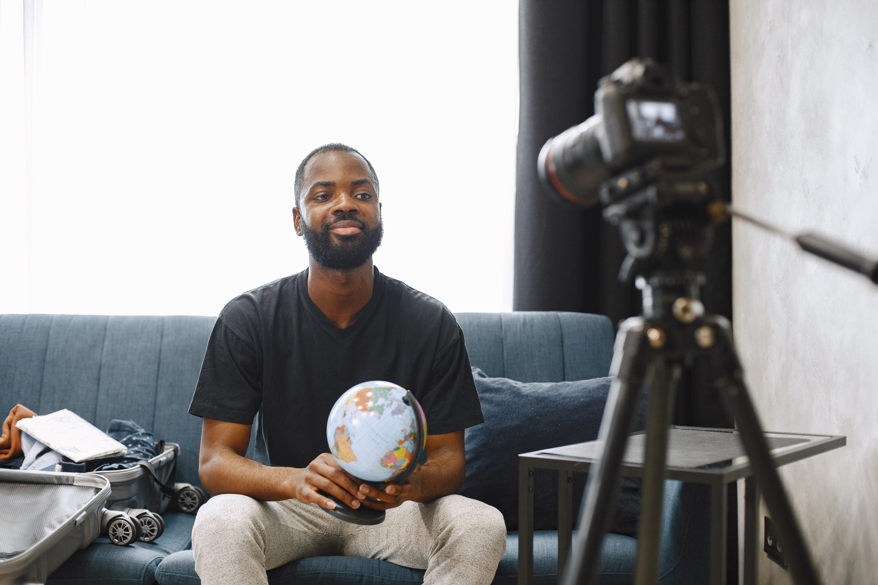 Male Vlogger holding a Globe while shooting a Video